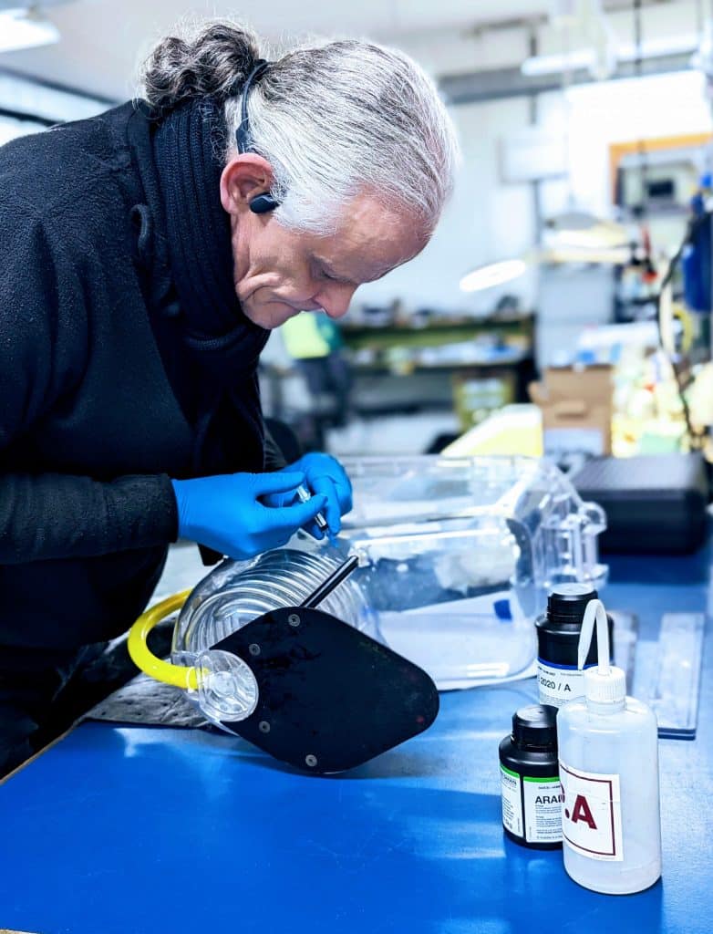 Technicus van MT Unirepair inspecteert en herstelt transparante technische component met slang en vloeistofflessen